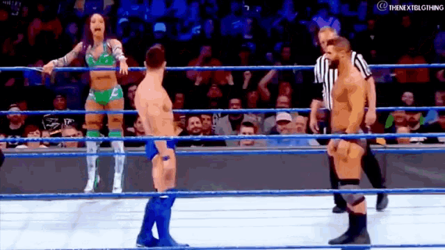 a man and a woman are standing in a wrestling ring with a referee