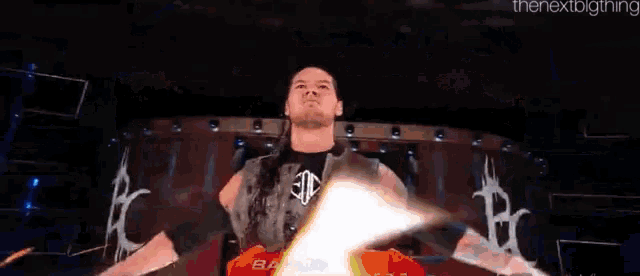 a wrestler is standing on a stage with his arms outstretched in front of a sign that says the nextbigthing