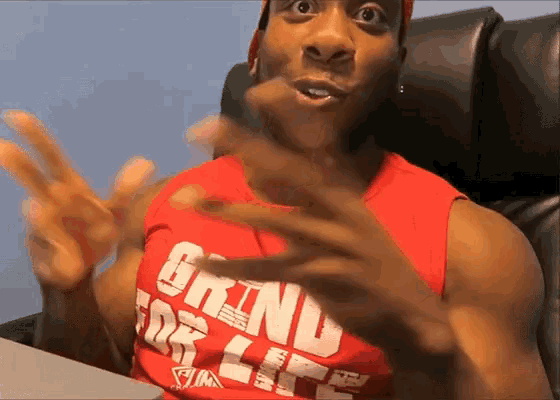 a man wearing a red tank top that says grind for life on it