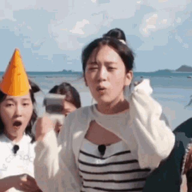 a woman wearing a party hat is standing on a beach .