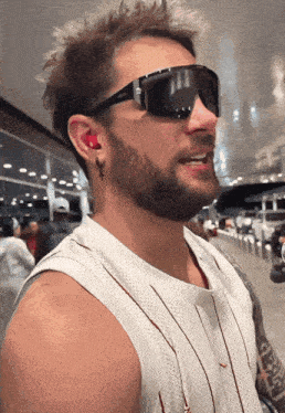 a man with a beard wearing sunglasses and a white shirt