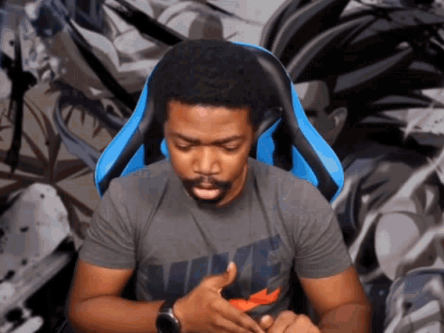 a man wearing a nike t-shirt sits in a blue chair