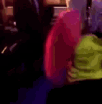 a blurry picture of a group of people standing in a room with purple lights .