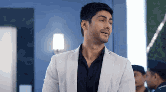 a man in a white jacket and black shirt