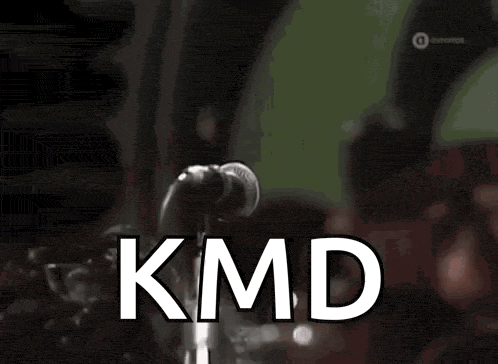 a man singing into a microphone with kmd written in white
