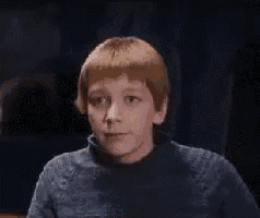 a young man with red hair is wearing a blue sweater and looking down .
