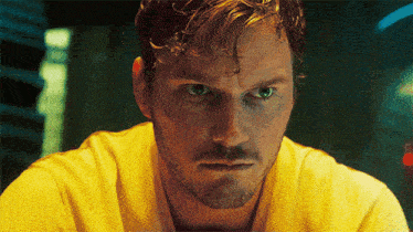a man with a beard and a yellow shirt is looking at the camera