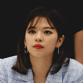 a close up of a woman wearing hoop earrings and a plaid jacket