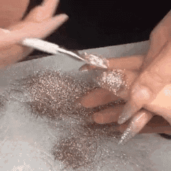 a woman is applying glitter to her nails .