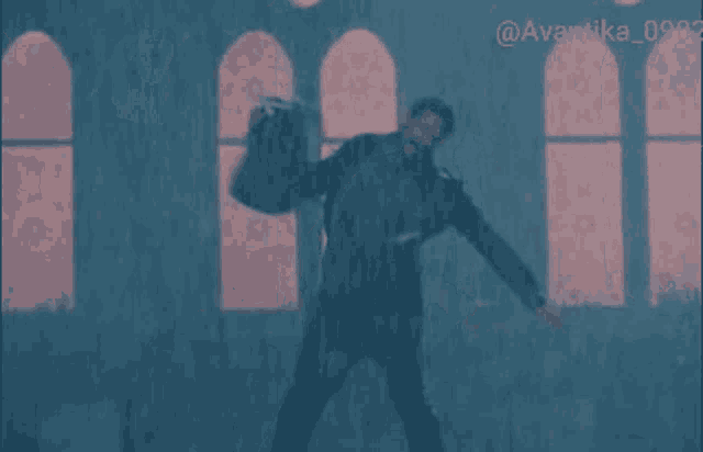 a man is dancing in the rain in front of a window with the numbers 0902 on it