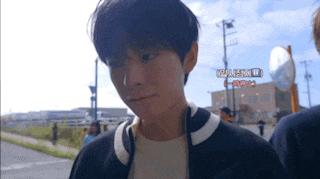 a young man walking down a street with a sign in the background that says ' osaka ' on it