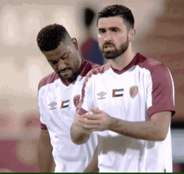 two soccer players are standing next to each other and one of them has the letter e on his shirt