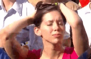 a woman in a pink shirt is holding her head in pain .
