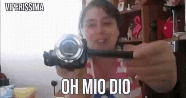 a woman is holding a video camera with the words oh mio dio above her