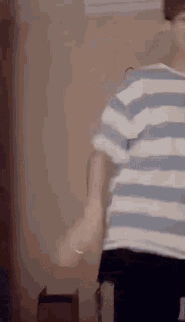 a man in a striped shirt is dancing in a room .