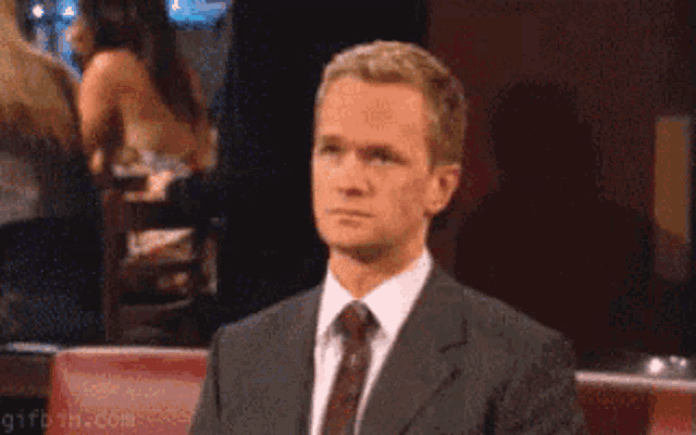 a man in a suit and tie is making a face with his hand .