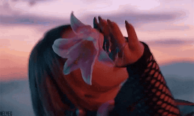a woman is covering her face with a flower .