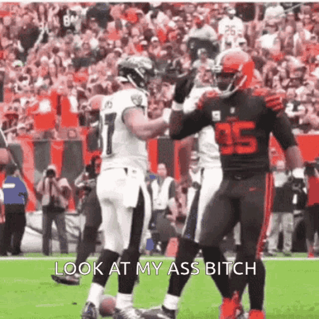two football players are high fiving each other on a field with the caption look at my ass bitch