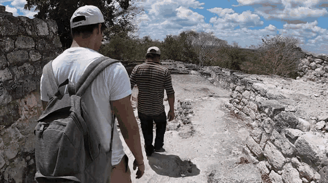 two men are walking down a path with a backpack