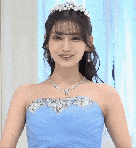 a woman wearing a blue dress and a tiara smiles