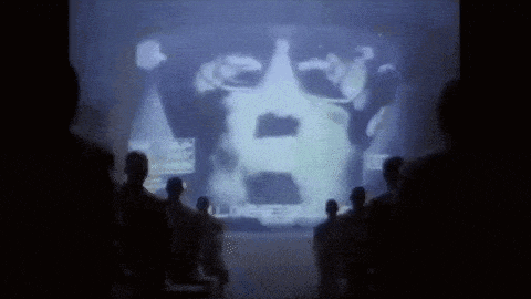 a group of people are standing in front of a large screen .