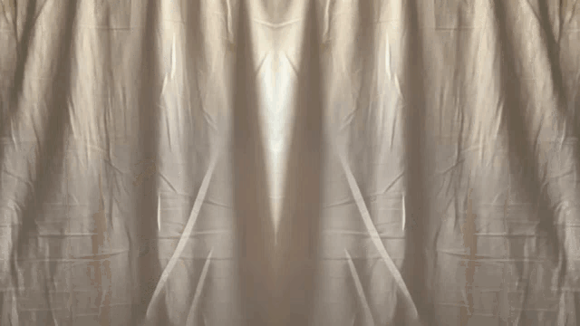 a man peeking out from behind a curtain with a few hundred dollar bills hanging from the ceiling