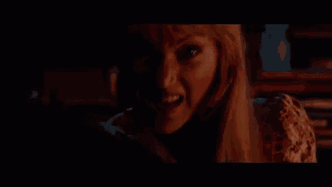 a woman with blonde hair is screaming in a dark room .