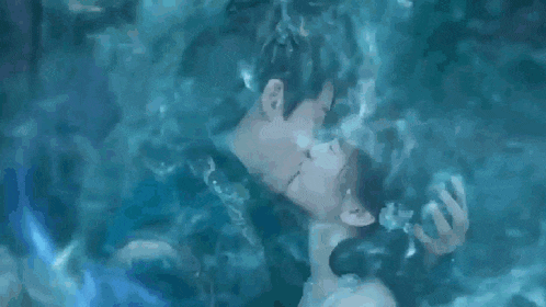 a man and a woman are kissing underwater .