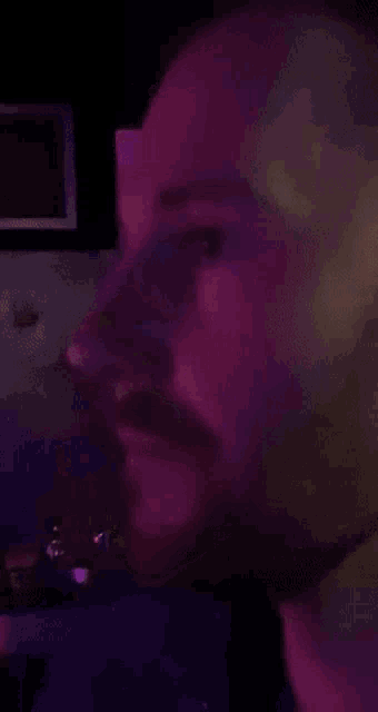 a man with a beard is smiling in a purple light