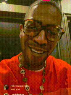 a man wearing glasses and a red shirt smiles