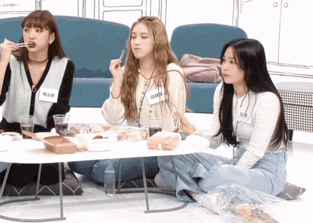 a girl with a name tag that says ' eunbi ' on it sits at a table with other girls