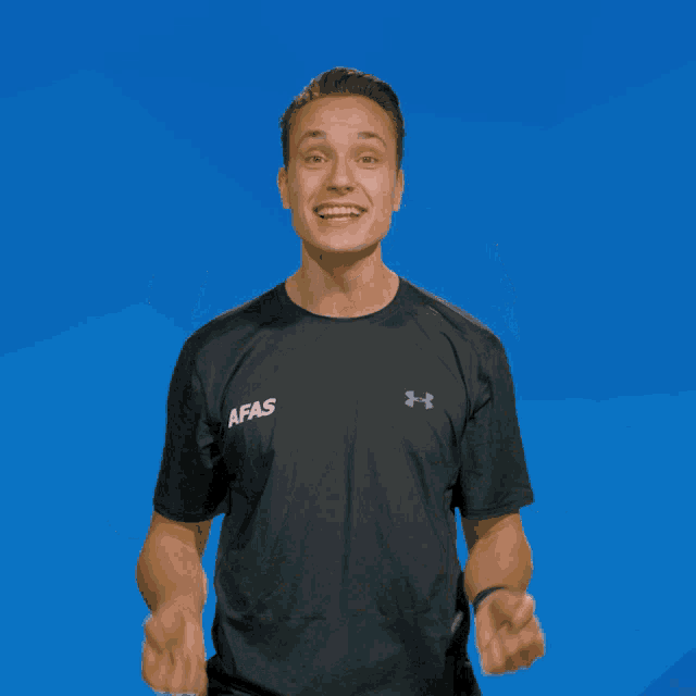 a man wearing a black afas shirt holds his fist up in the air