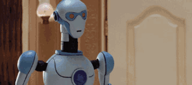 a blue and white robot with red eyes standing in front of a door