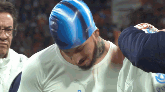 a man wearing a blue swim cap and a white shirt with the letter c on it