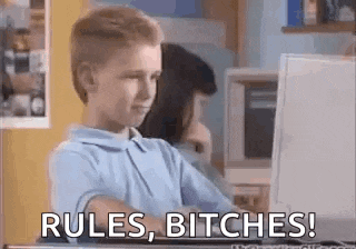 a young boy is sitting in front of a computer with the words `` rules , bitches '' written on the screen .