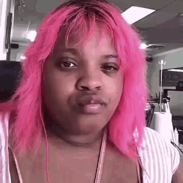 a woman with pink hair is making a funny face while sitting in a chair .