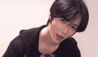 a young man with short black hair is looking at the camera with his mouth open .