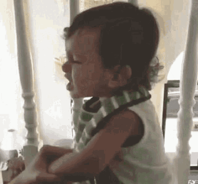 a baby is crying while wearing a bib and sitting on a chair .