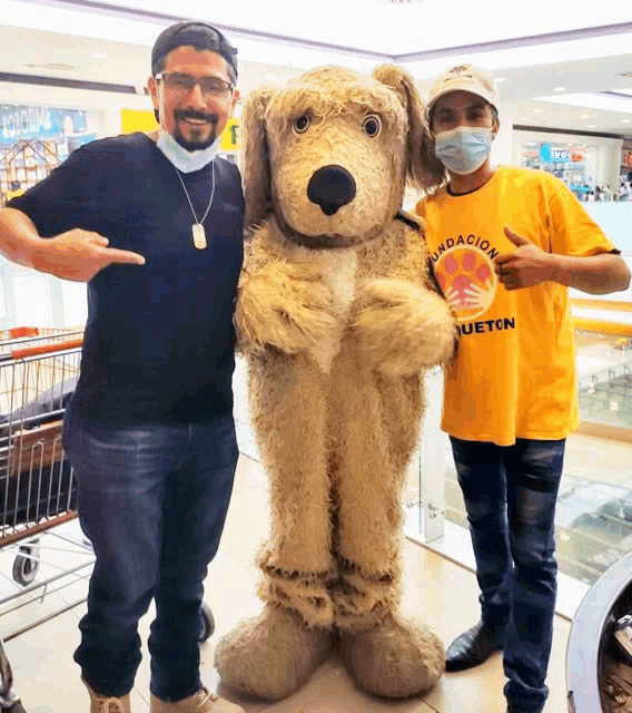 a man wearing a yellow t-shirt that says " fundacion " stands next to a stuffed dog