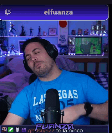a man wearing headphones and a blue las vegas shirt is sitting in front of a microphone