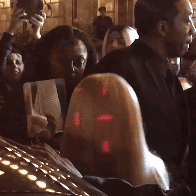 a woman taking a picture of herself in a mirror in a crowd