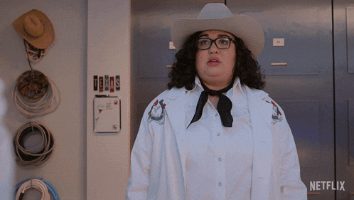 a woman wearing a cowboy hat and glasses is standing in front of a netflix logo