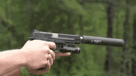 a close up of a person holding a gun with a silencer attached to it .