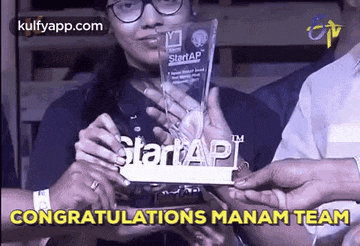 a woman is holding a trophy that says congratulations manam team on it