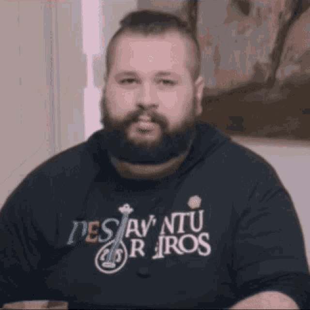 a man with a beard is wearing a shirt that says des av ntu r iros