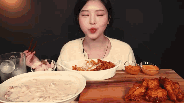 a woman is sitting at a table eating a bowl of food with chopsticks