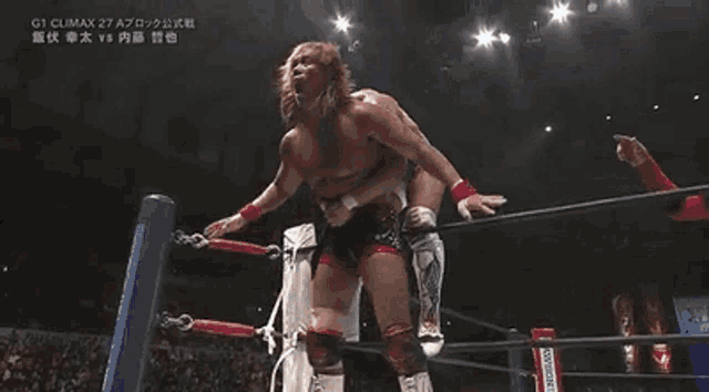 a wrestler is doing a flip in a wrestling ring with a referee watching .