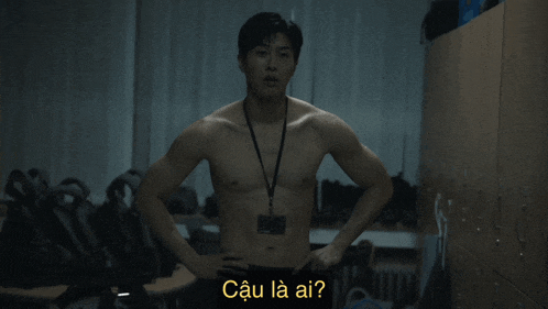 a shirtless man with a lanyard around his neck is standing in a dark room with the words cau la ai written on the bottom
