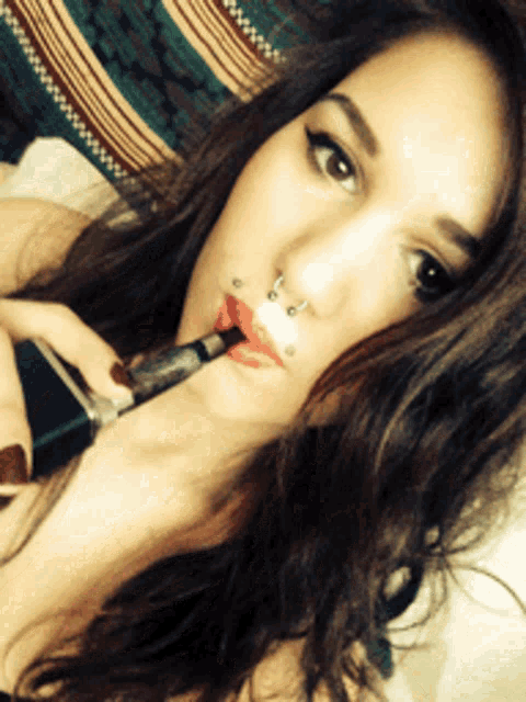 a woman with a nose ring is smoking an e-cigarette