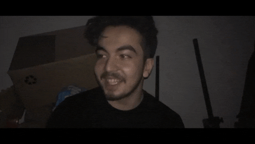 a man with a beard is smiling in the dark